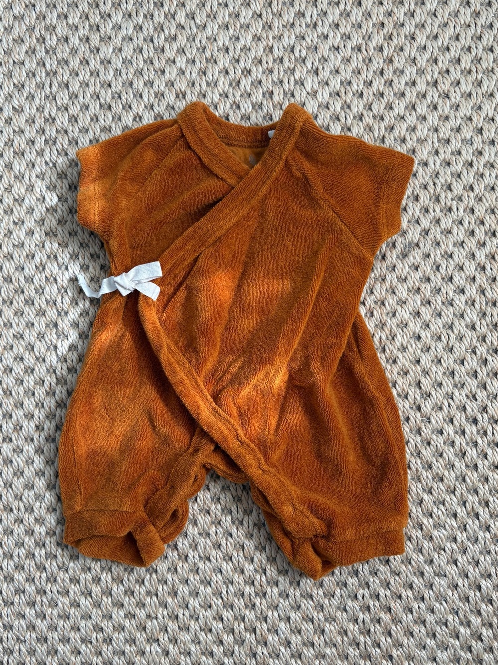 Newborn onesie in ochre terrycloth with snap closure